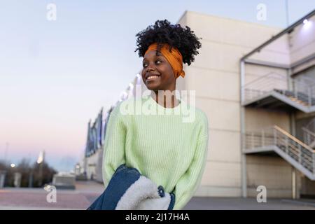 Curly haired woman holding denim jacket at sunset Stock Photo