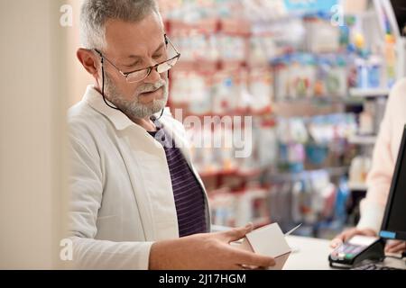 Pharmacist reading instructions on medicine box at pharmacy store Stock Photo