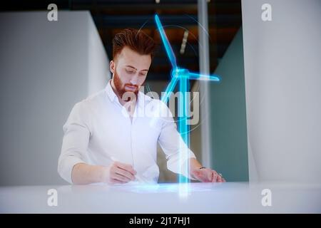Engineer working on digital display by wind turbine at desk in control room Stock Photo