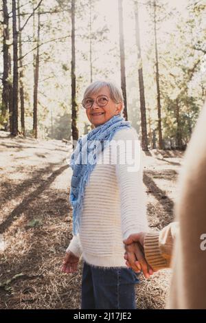 Smiling senior couple holding hands in forest Stock Photo