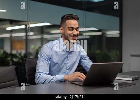 Cheerful middle eastern manager typing on notebook Stock Photo