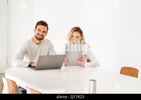 Cheerful young freelancers with wireless technologies sitting at table Stock Photo