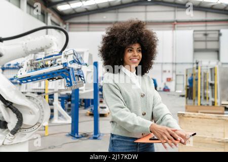 Smiling engineer holding file standing in factory Stock Photo
