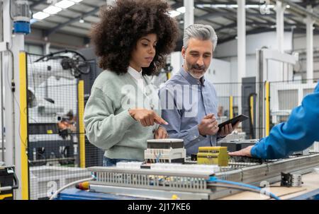 Engineer with technicians discussing about machine in factory Stock Photo