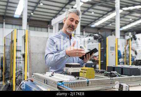 Developer discussing about machine through video call on tablet PC in factory Stock Photo