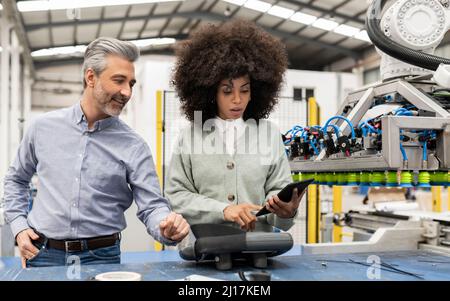 Developer using tablet PC standing by technician in factory Stock Photo