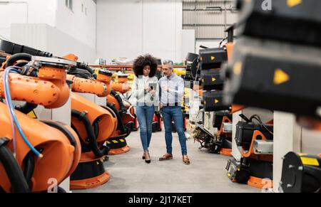 Engineer using tablet PC and discussing with technician standing in factory Stock Photo