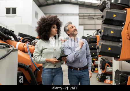 Technicians analyzing machinery in factory Stock Photo