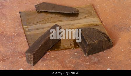 Hashish, four different sized servings of cannabinoid narcotic substance containing THC called hashish cost chocolate on brick background. Drug addict Stock Photo