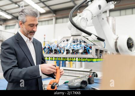 Engineer examining robotic arm model in factory Stock Photo