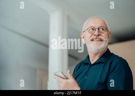 Happy senior man holding smart phone in office Stock Photo