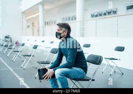 Businessman wearing protective face mask with tablet PC in corridor Stock Photo