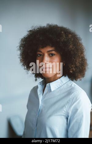 Confident businesswoman with curly hair at work place Stock Photo