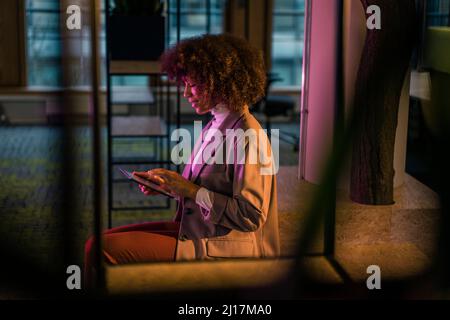Businesswoman using tablet computer in illuminated office Stock Photo