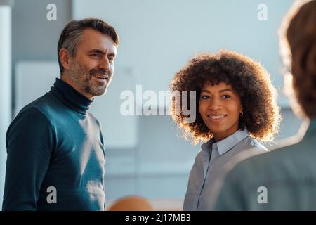 Smiling multiracial colleagues looking at businessman in office Stock Photo