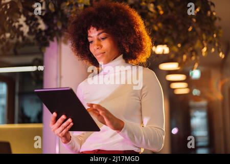 Businesswoman using tablet computer at illuminated work place Stock Photo