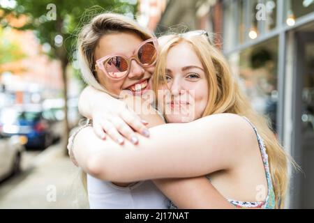 Happy teenage girls with blond hair hugging each other Stock Photo