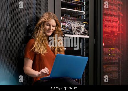 Smiling blond IT support using laptop in server room Stock Photo
