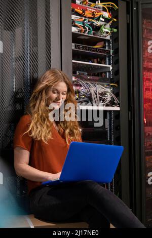Smiling IT support using laptop in server room Stock Photo
