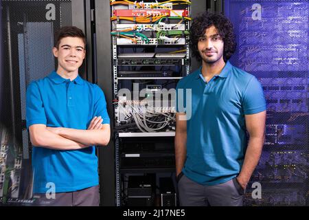 Smiling technician colleagues standing in server room Stock Photo