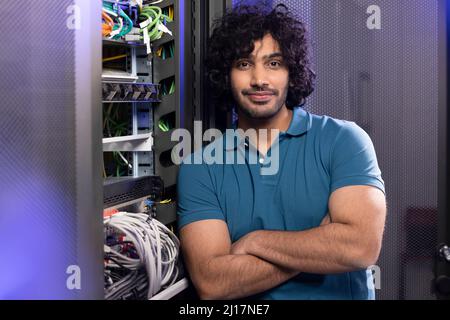 Technician with arms crossed standing in server room Stock Photo