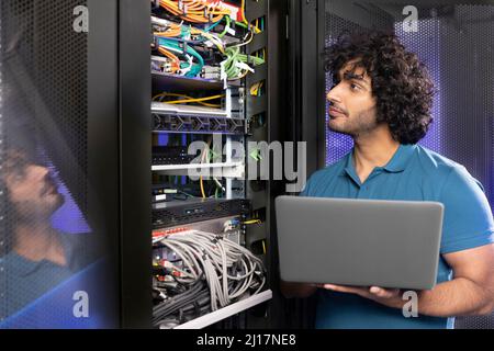 IT support holding laptop checking network server in industry Stock Photo
