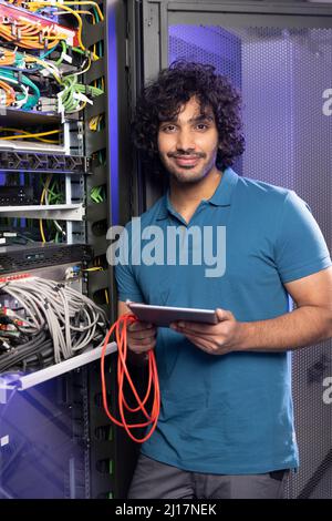 Smiling IT technician holding tablet PC standing in server room Stock Photo