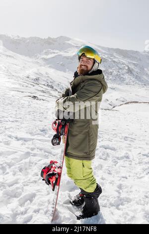 Portrait of a young man holding a snowboard looking at camera Stock ...