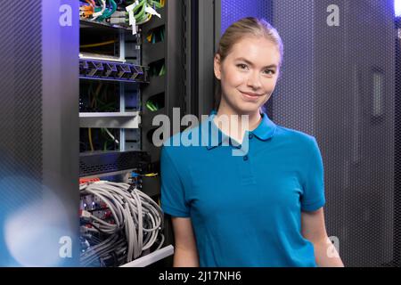Happy technician standing in server room at industry Stock Photo