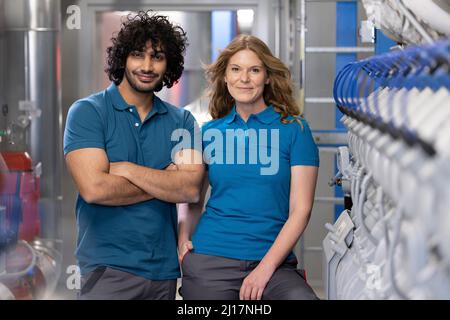 Smiling technician colleagues standing together at factory Stock Photo