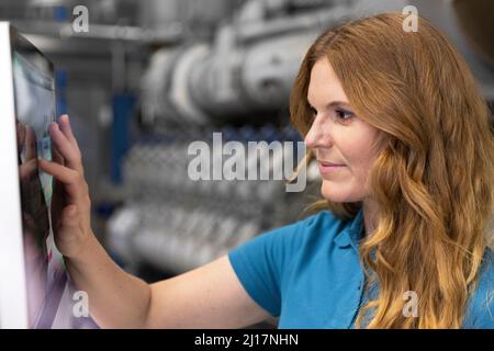 Blond IT technician using touch screen device in factory Stock Photo