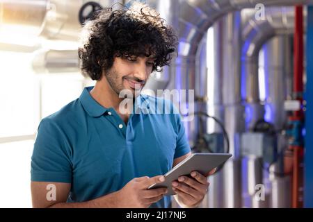 Smiling technician holding tablet PC standing in factory Stock Photo