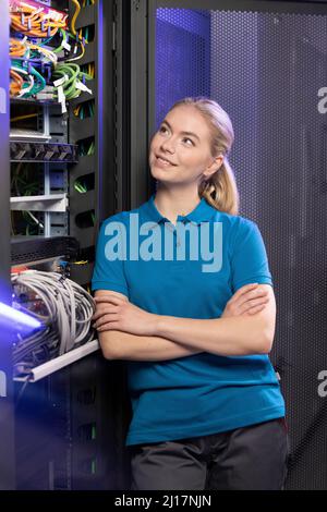 Smiling technician standing with arms crossed in server room at industry Stock Photo