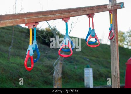 Multicolored gymnastic rings in a playground for outdoor sports, on a wooden bar horizontally Stock Photo