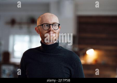 Thoughtful young businessman wearing eyeglasses standing in office Stock Photo