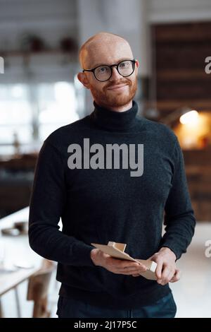 Smiling businessman with wooden model standing in office Stock Photo