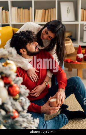 Smiling woman embracing boyfriend from behind at home Stock Photo