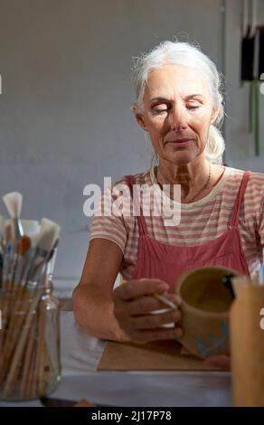 Woman holding clay pot sitting at table Stock Photo