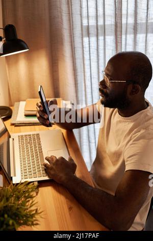 Businessman text messaging through smart phone working at home office Stock Photo