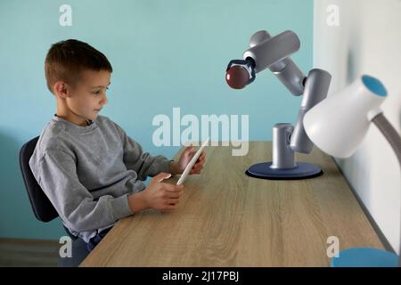 Boy controlling robotic arm through table PC at home Stock Photo