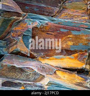 Realistic abstract colour photograph of coastal rocks stones beach sculptured by the passages of time and tide with grained patterns and textures Stock Photo