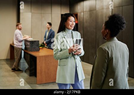 Business colleagues talking to each other standing in office lobby Stock Photo