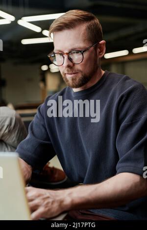 Concentrated businessman with eyeglasses working on laptop at office Stock Photo