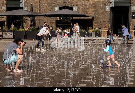 London, UK. 23rd Mar, 2022. A young boy cools down by running through the Granary Square fountain with his scooter as the temperatures reach 20 degrees again today in the capital. Picture Credit: ernesto rogata/Alamy Live News