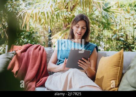 Businesswoman using tablet computer sitting on sofa Stock Photo