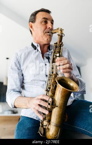 Musician playing saxophone at home Stock Photo
