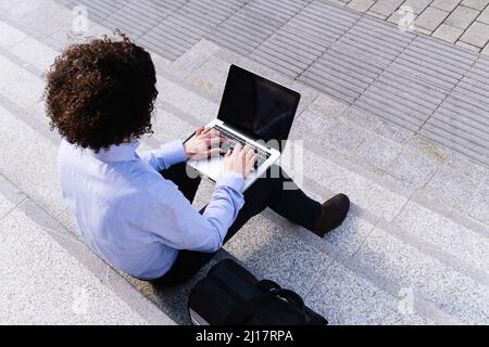 Businessman using laptop sitting on steps Stock Photo