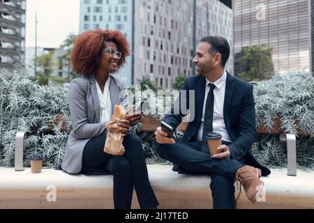 Two business colleagues talking while sitting outdoors Stock Photo