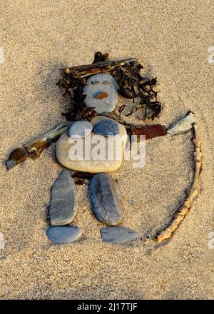 Colour photograph of human female crafted by using beach materials such as wood seaweed coastal stones on beach smoothed and rounded by the passages o Stock Photo