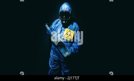 man wears a nuclear suit and in his hand he has a bottle of vodka Stock Photo